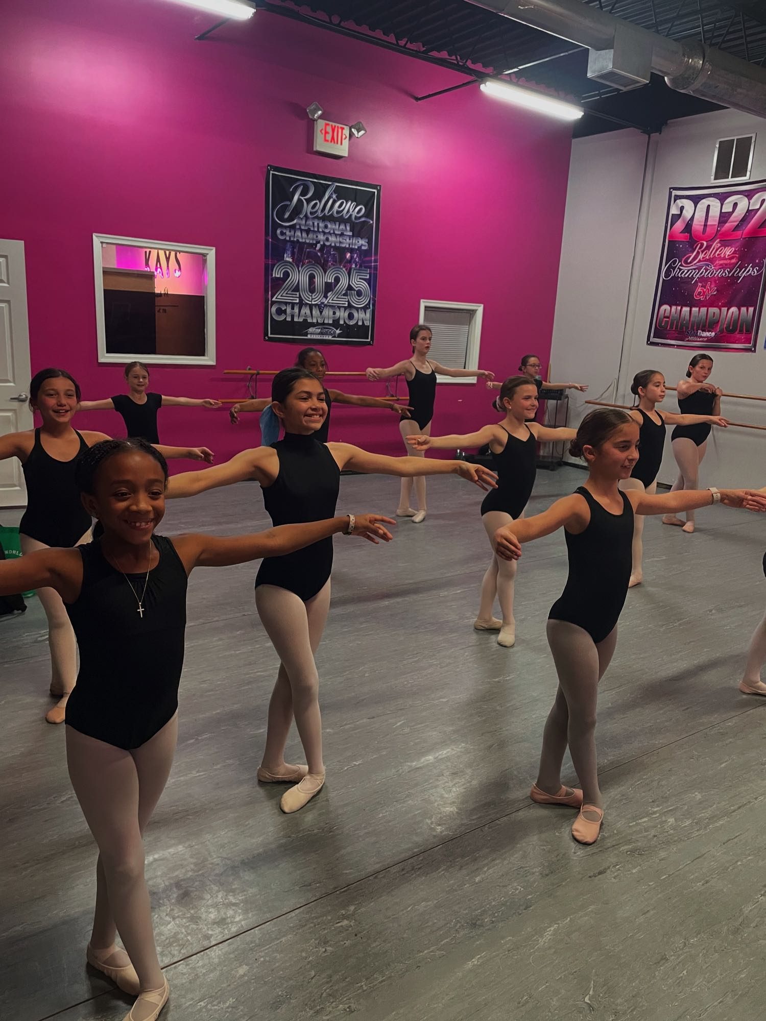 Ballet class at the barre at Kay's Act II, national championship banners on the pink studio wall