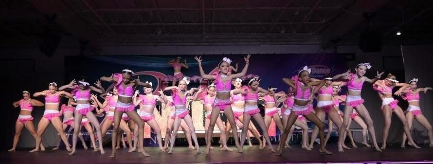 Kay's Act II competitive team performing on stage in pink costumes